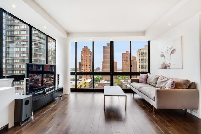 living room featuring a view of city, floor to ceiling windows, recessed lighting, and wood finished floors