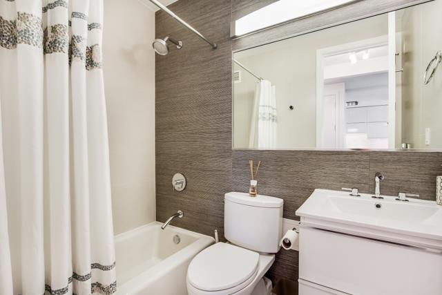 full bathroom featuring tile walls, toilet, vanity, and shower / tub combo