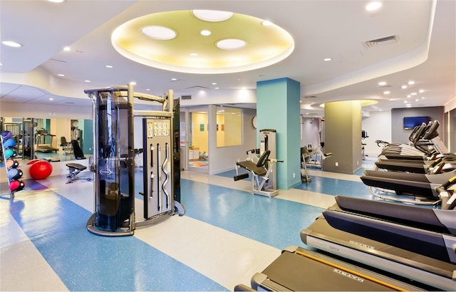 exercise room with recessed lighting, a tray ceiling, and visible vents