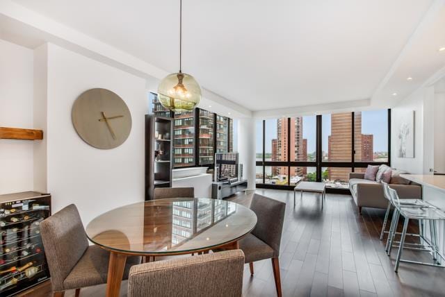 dining area with a city view, a wall of windows, wine cooler, and wood finished floors