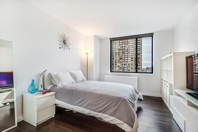 bedroom featuring baseboards and dark wood-style flooring