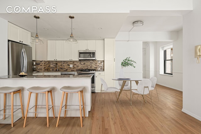 kitchen with backsplash, appliances with stainless steel finishes, a breakfast bar area, and a peninsula