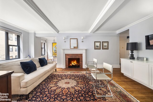 living room with beam ceiling, crown molding, and wood finished floors