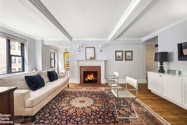 living room featuring a brick fireplace, beamed ceiling, ornamental molding, and wood finished floors