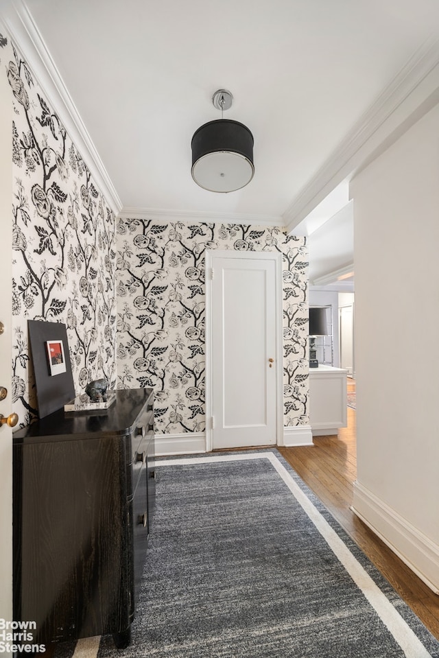 interior space featuring crown molding, baseboards, wood finished floors, and wallpapered walls