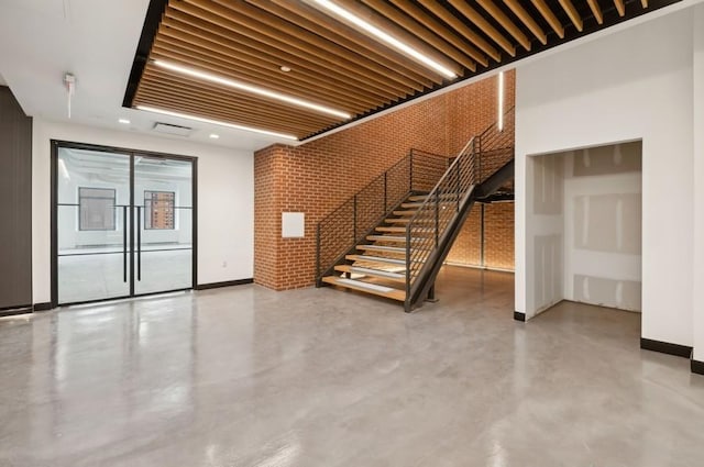 interior space with stairs, visible vents, baseboards, and brick wall