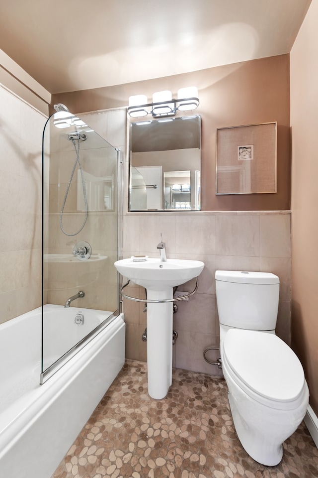 full bath featuring tile walls, toilet, and bath / shower combo with glass door