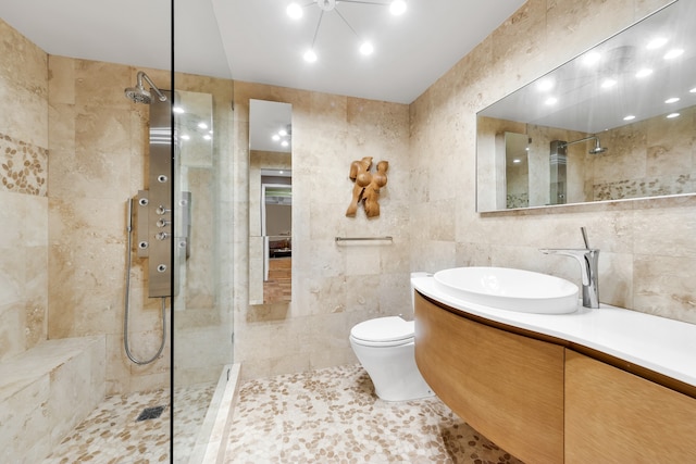 bathroom with tile walls, toilet, vanity, a walk in shower, and tile patterned flooring