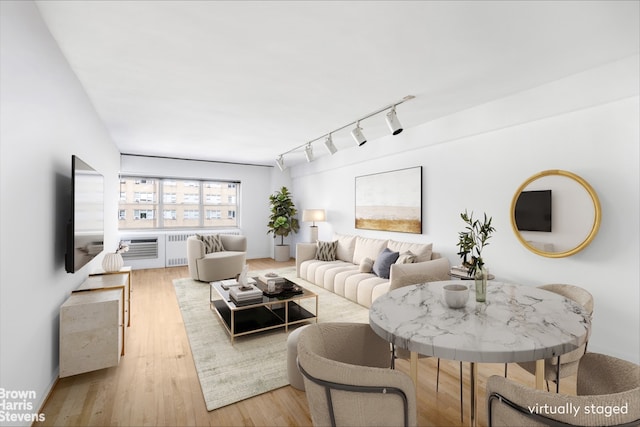 living room featuring track lighting, radiator heating unit, and light wood-style floors