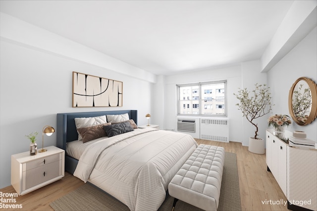 bedroom with radiator and light wood finished floors