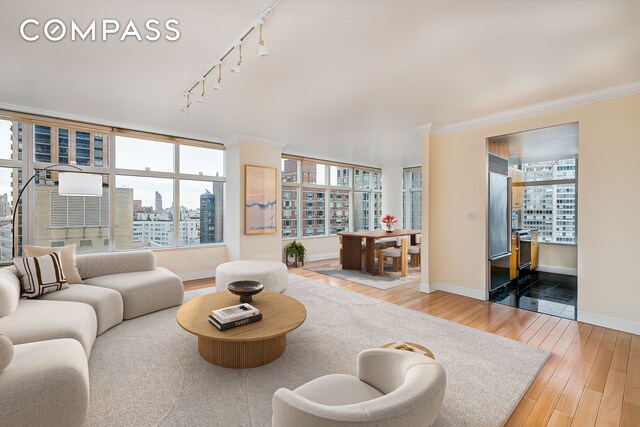 160 W 66th St Unit 23D, New York City, NY 10023 - living room with a view of city, wood finished floors, rail lighting, crown molding, and baseboards