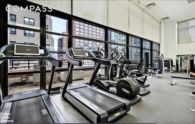 exercise room with a city view, a high ceiling, and visible vents