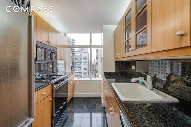 kitchen featuring a sink, range with gas stovetop, granite finish floor, freestanding refrigerator, and black microwave