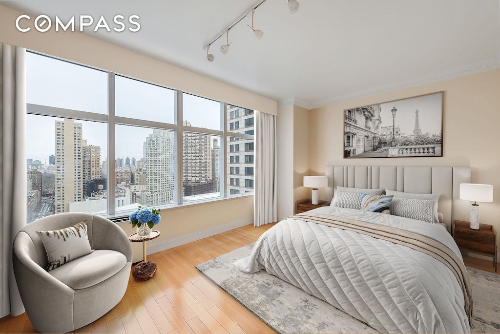 160 W 66th St Unit 23D, New York City, NY 10023 - bedroom featuring a city view, wood finished floors, track lighting, and ornamental molding
