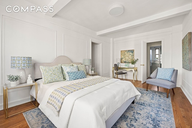 bedroom with beamed ceiling, wood finished floors, and baseboards