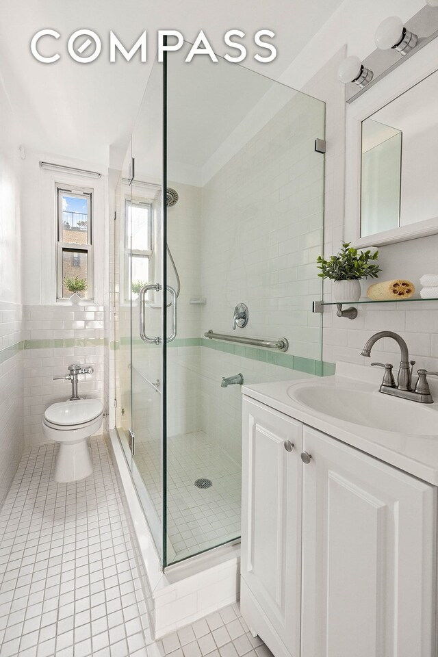 bathroom with toilet, tile patterned floors, vanity, a shower stall, and tile walls