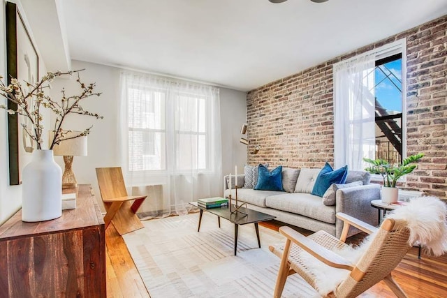 living area with brick wall and wood finished floors