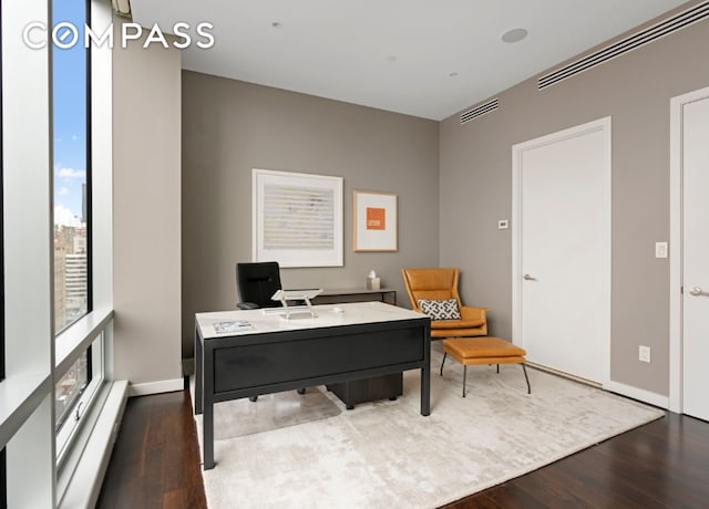 office area with wood finished floors, visible vents, and baseboards