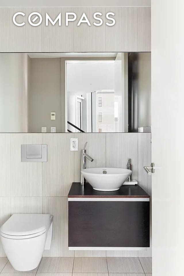 bathroom with toilet, vanity, and tile walls