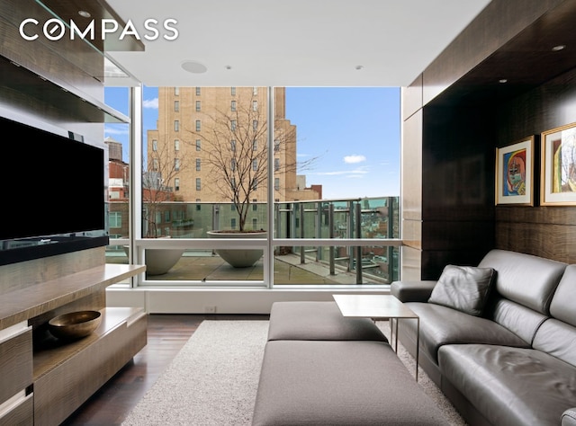 living area featuring a healthy amount of sunlight, a wall of windows, and wood finished floors