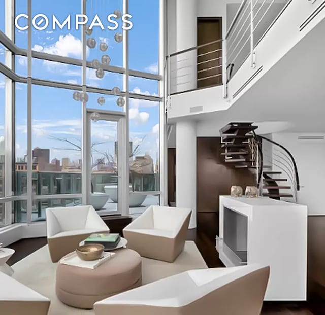 living room with visible vents, wood finished floors, a towering ceiling, and floor to ceiling windows