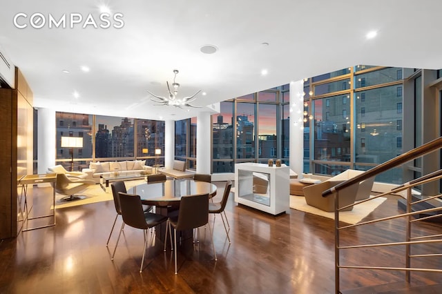 dining room featuring a wall of windows, a city view, an inviting chandelier, and wood finished floors