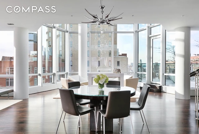 dining area featuring expansive windows, a city view, wood finished floors, and an inviting chandelier