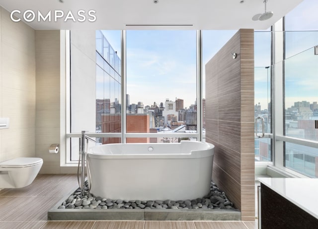 full bath featuring a view of city, toilet, vanity, tile patterned flooring, and a freestanding tub