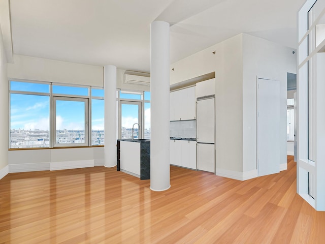 interior space featuring baseboards, a wall unit AC, a city view, light wood-style floors, and a sink