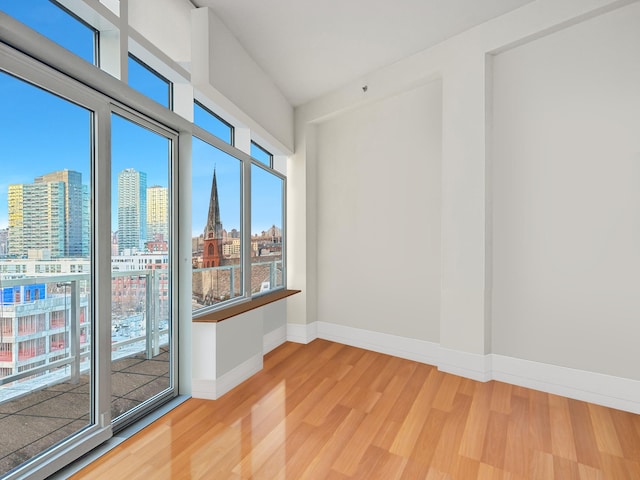 spare room featuring a view of city, baseboards, and light wood-style floors