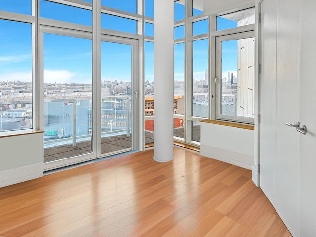 spare room with a view of city and wood finished floors