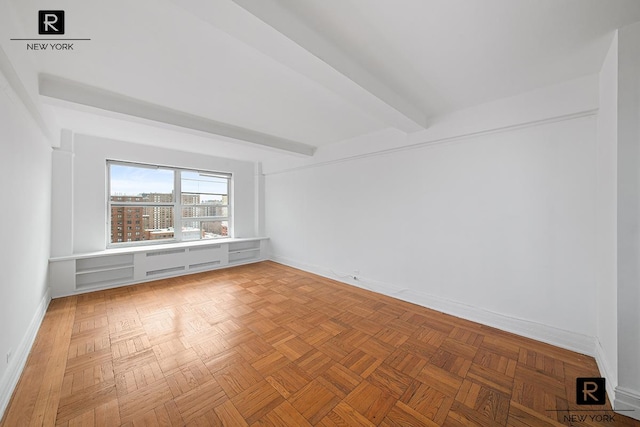 spare room with beam ceiling and baseboards