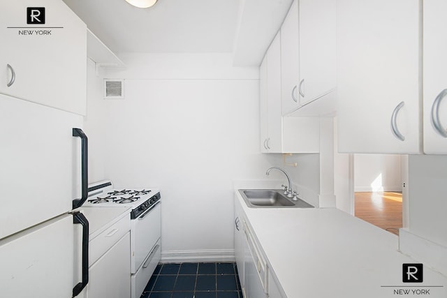 kitchen featuring white appliances, visible vents, white cabinets, light countertops, and a sink