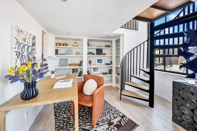 office area with built in shelves, plenty of natural light, and wood finished floors