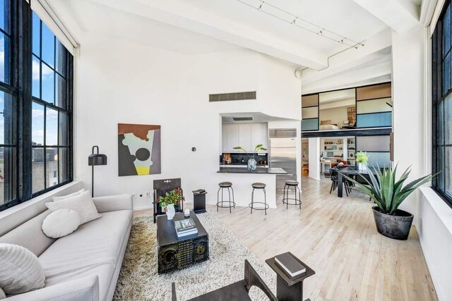 111 4th Ave Unit 7I, New York City, NY 10003 - living room featuring wood finished floors, track lighting, beamed ceiling, a high ceiling, and visible vents