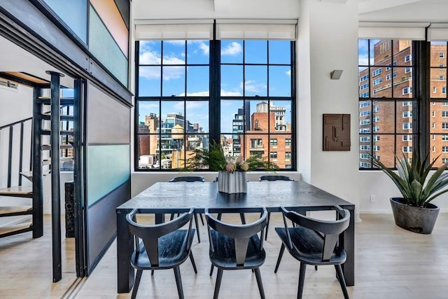 dining space with baseboards, wood finished floors, stairs, a view of city, and a high ceiling