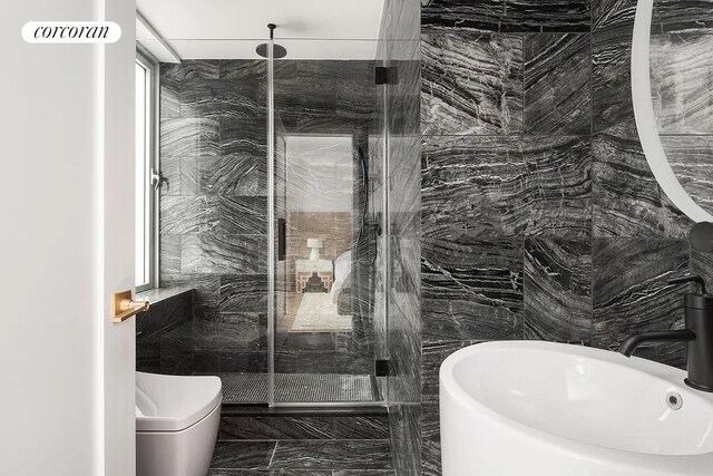 bathroom with a sink, tile walls, and a marble finish shower