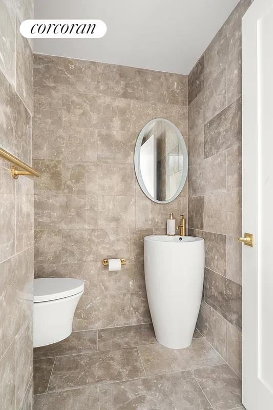 bathroom featuring toilet and tile walls