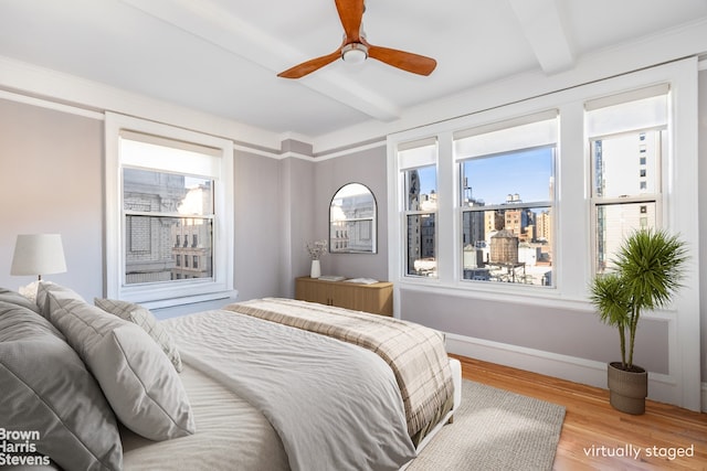 bedroom featuring beamed ceiling, baseboards, wood finished floors, and a ceiling fan