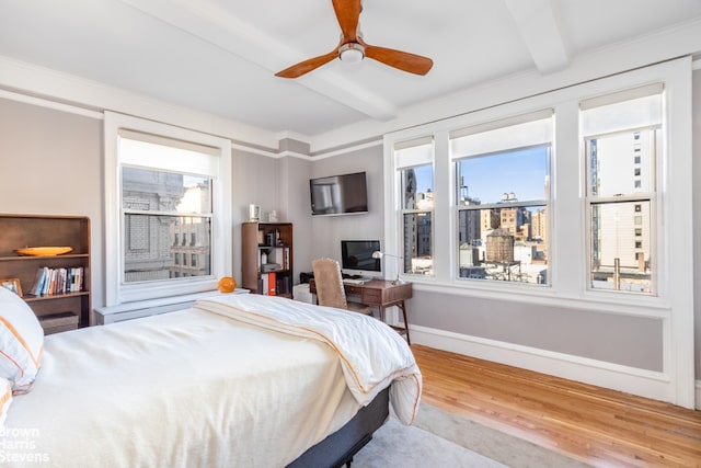 bedroom with ceiling fan, beamed ceiling, baseboards, and wood finished floors