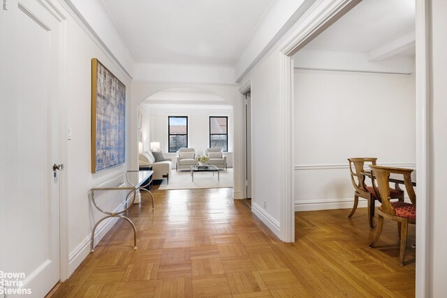 hallway featuring arched walkways and baseboards