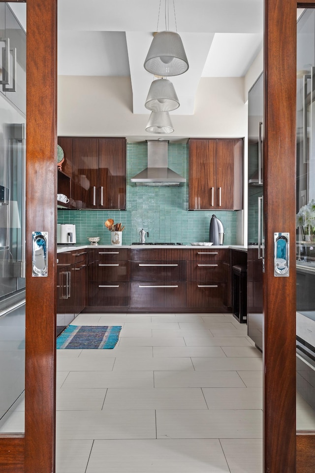 kitchen with tasteful backsplash, wall chimney exhaust hood, modern cabinets, and light countertops