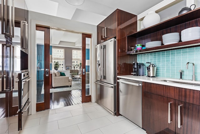 kitchen with stainless steel appliances, tasteful backsplash, light countertops, a sink, and modern cabinets