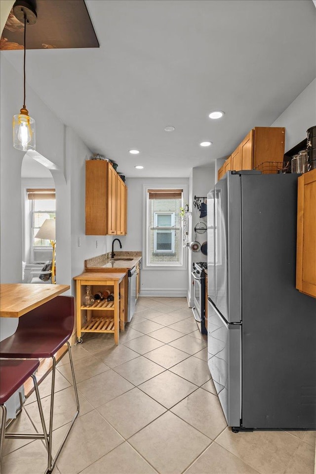 811 Walton Ave Unit F19, New York City, NY 10451 - kitchen with stainless steel appliances, arched walkways, light tile patterned flooring, a sink, and light countertops
