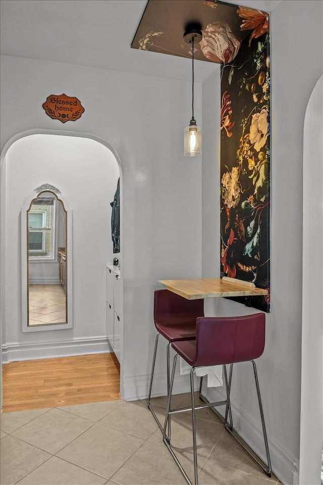 tiled dining room with arched walkways and baseboards