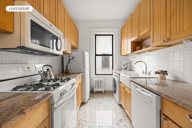 kitchen with tasteful backsplash, radiator, washer / dryer, white appliances, and a sink