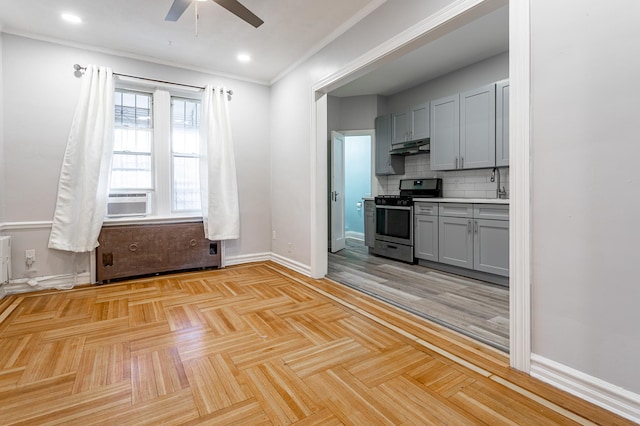 kitchen with stainless steel gas range oven, tasteful backsplash, baseboards, under cabinet range hood, and gray cabinets