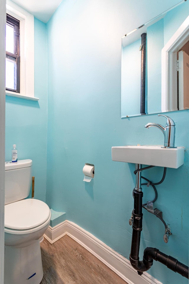 half bath with a sink, toilet, baseboards, and wood finished floors