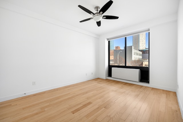 spare room with light wood-style floors, baseboards, and a ceiling fan