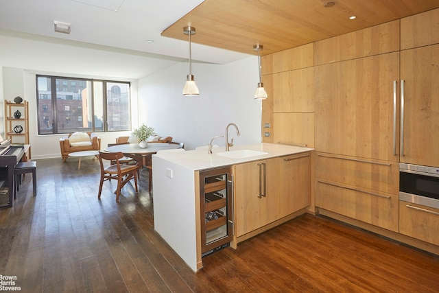 kitchen featuring beverage cooler, a peninsula, dark wood-style flooring, a sink, and wall oven